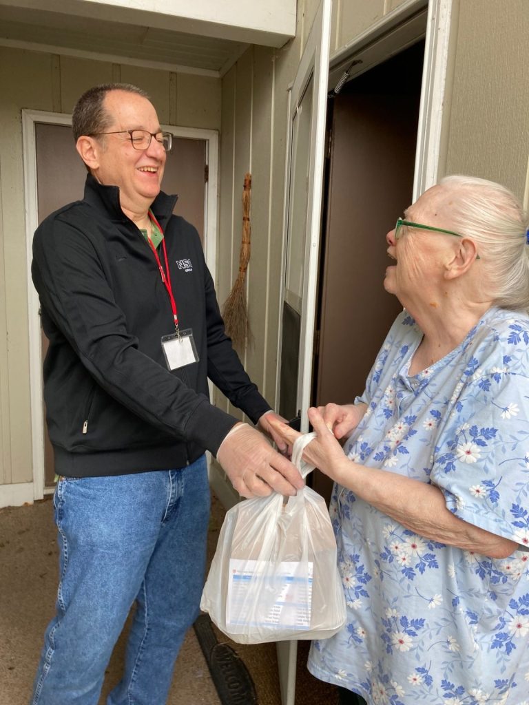 Photo of a man delivering food to an elderly woman.